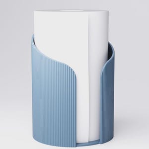 May include: A light blue, cylindrical paper towel holder with vertical ribbed detailing. The holder has a curved opening and holds a roll of white paper towels. The design is modern and minimalist.