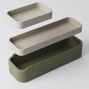 Peut inclure: Un ensemble de trois bo&icirc;tes de rangement. L'ensemble comprend deux plateaux rectangulaires beiges clairs et un grand conteneur vert olive avec des d&eacute;tails c&ocirc;tel&eacute;s verticaux. Les plateaux semblent flotter au-dessus du conteneur.