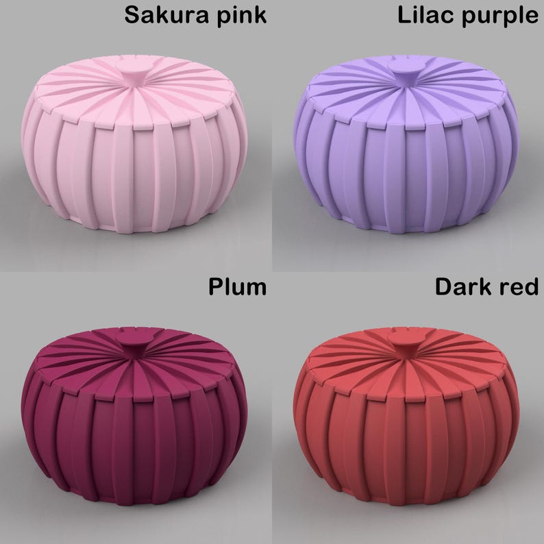 May include: Four decorative, round ottomans in various colors: Sakura pink, lilac purple, plum, and dark red. Each ottoman has a ribbed, pleated design and a small, round top. The text labels each color.