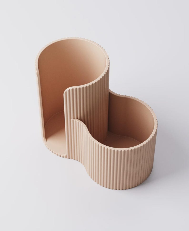 Puede incluir: Un organizador de escritorio melocot&oacute;n en forma de onda con una textura acanalada. El organizador tiene tres compartimentos de diferentes tama&ntilde;os, perfectos para guardar bol&iacute;grafos, l&aacute;pices u otros &uacute;tiles de oficina. El dise&ntilde;o es moderno y minimalista.
