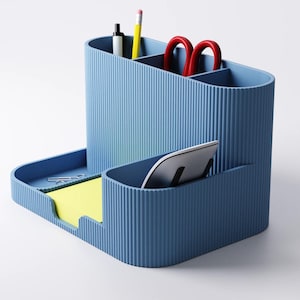 May include: A blue desk tidy with a ribbed texture. It has compartments for pens, pencils, and scissors, plus a tray for sticky notes and a slot for a tablet or phone. The organiser is a solid blue colour.