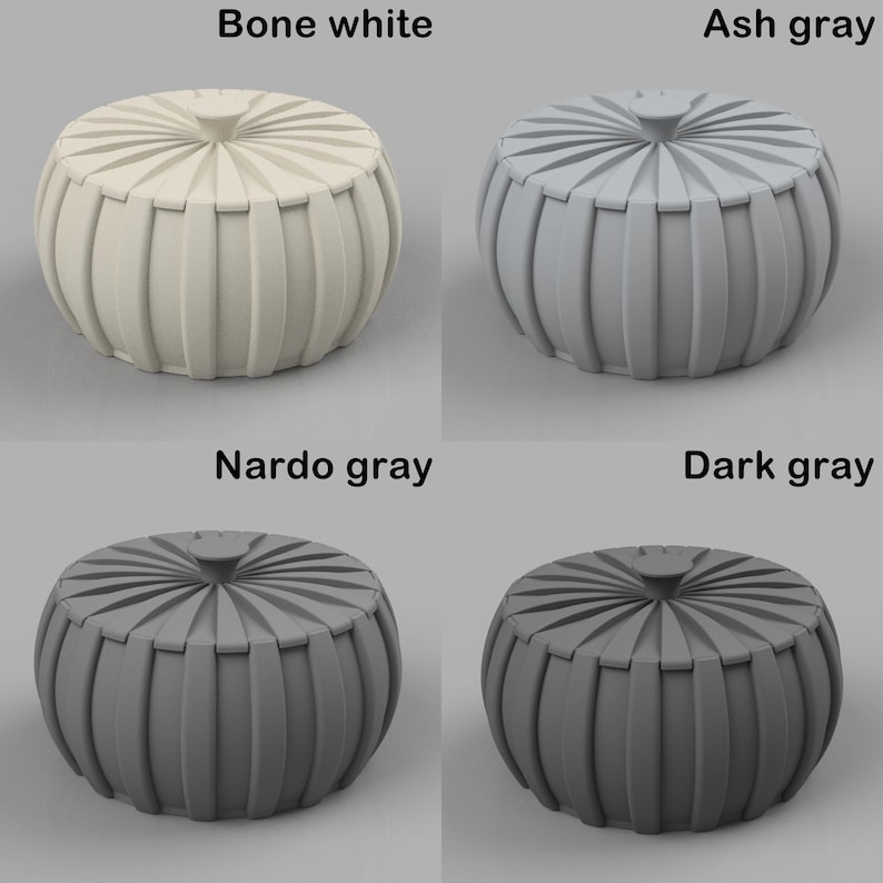 May include: Four decorative poufs in bone white, ash grey, Nardo grey, and dark grey. Each pouf has a round shape with vertical ribbed sides and a circular top with a central button. The image displays the poufs against a neutral background.