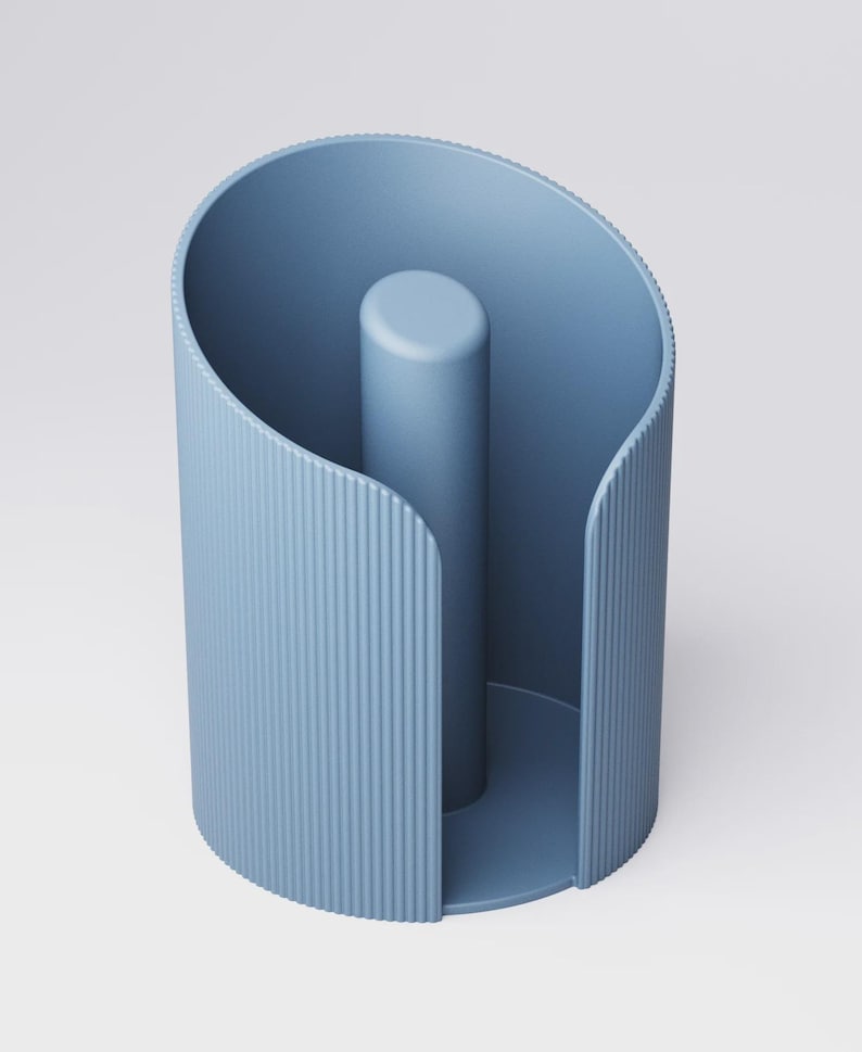 May include: A blue paper towel holder with a vertical central post. The holder has a curved, open design with vertical ridged detailing on the sides. The holder is made of a solid, matte material.
