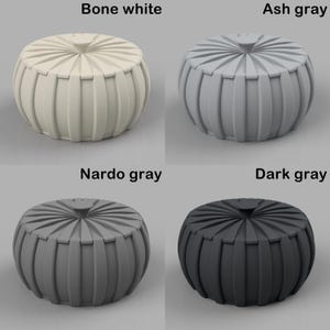 Puede incluir: Cuatro pufs decorativos en blanco hueso, gris ceniza, gris Nardo y gris oscuro. Cada puf tiene forma redonda con detalles acanalados verticales alrededor de los lados y una parte superior circular. Los colores est&aacute;n etiquetados encima de cada puf.