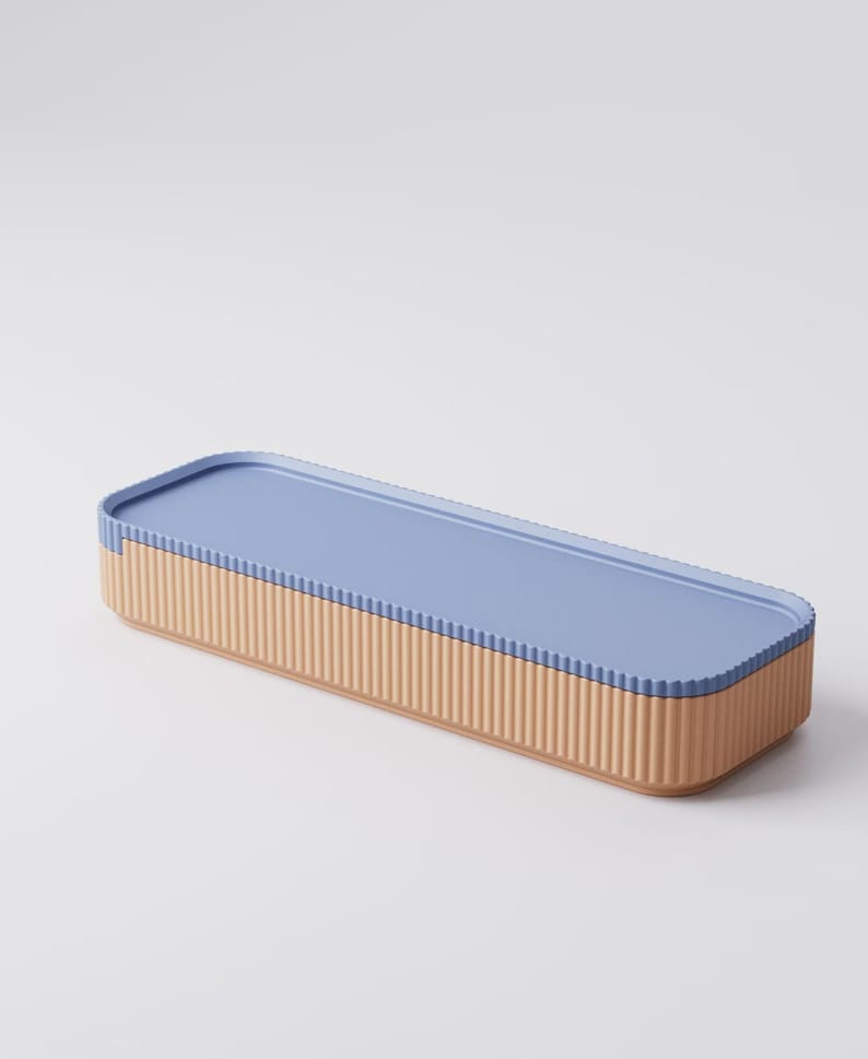 Puede incluir: Una caja de almacenamiento rectangular con tapa azul claro y base beige con estr&iacute;as verticales. La caja tiene un dise&ntilde;o limpio y moderno, adecuada para organizar objetos peque&ntilde;os. La tapa encaja a ras con la base.