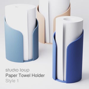 May include: Three modern paper towel holders in blue, beige, and navy blue. Each holder has a cylindrical shape with a white paper towel roll inside. The holders have a curved, ribbed design. The text "studio loup Paper Towel Holder Style 1" is visible.