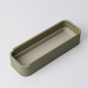 Peut inclure: Un plateau de rangement rectangulaire vert olive avec un ext&eacute;rieur nervur&eacute; et un int&eacute;rieur beige clair. Le plateau a des coins arrondis et un design minimaliste, adapt&eacute; pour organiser de petits objets.