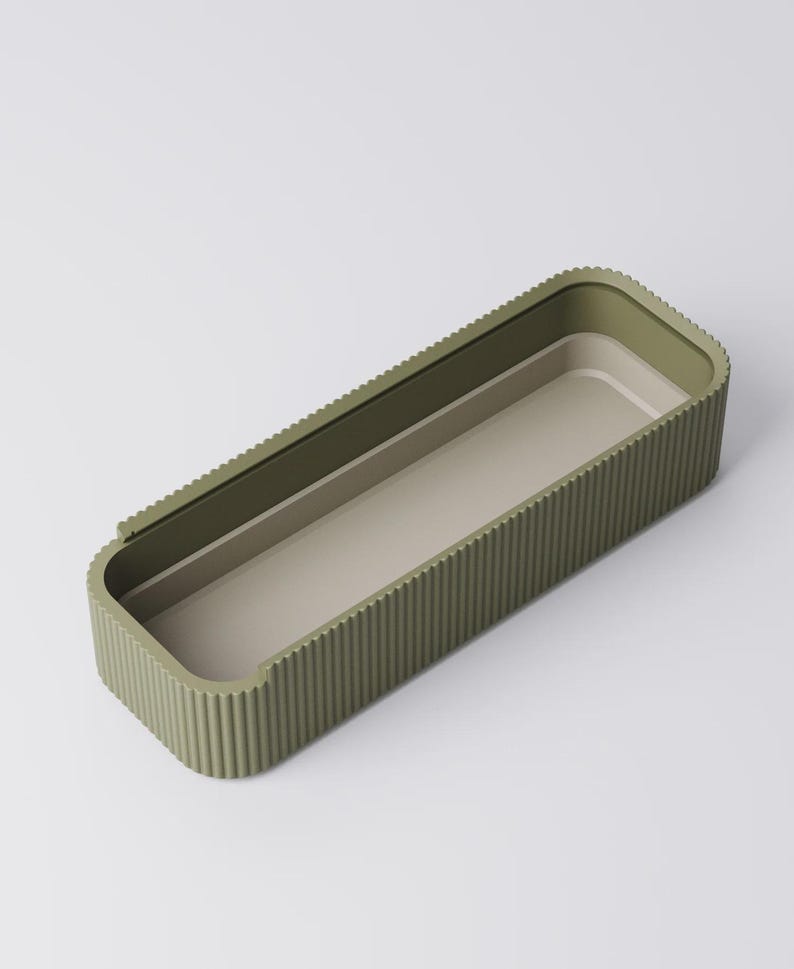 Peut inclure: Un plateau de rangement rectangulaire vert olive avec un ext&eacute;rieur nervur&eacute; et un int&eacute;rieur beige clair. Le plateau a des coins arrondis et un design minimaliste, adapt&eacute; pour organiser de petits objets.