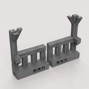 Op de afbeelding: Twee grijze heksecties in houten stijl. Elke sectie heeft een basis met drie rechthoekige openingen, verticale palen en een horizontale bovenrail. De palen zijn gelijkmatig verdeeld en de bovenkant van elke verticale paal heeft een decoratief, gestileerd ontwerp.