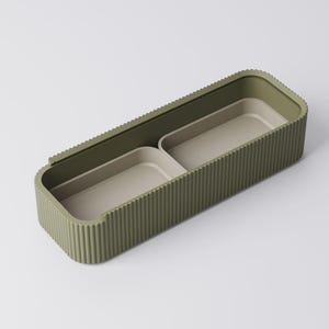 Peut inclure: Un conteneur de rangement rectangulaire vert olive avec un ext&eacute;rieur nervur&eacute; et deux compartiments int&eacute;rieurs. Les compartiments int&eacute;rieurs sont de couleur beige clair. Le conteneur est con&ccedil;u pour organiser de petits objets.