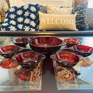 Puede incluir: Juego de seis cuencos de vidrio rojo con asas. Los cuencos son todos del mismo tamaño y tienen un diseño acanalado.