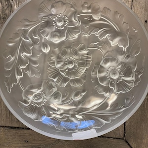 May include: A clear glass serving bowl with an etched floral design featuring poppies. The bowl has a frosted finish and a round shape.