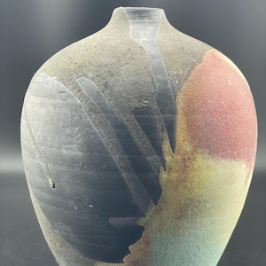 以下が含まれることがあります： 広口で首が細い丸い陶器の花瓶。花瓶は黒、赤、黄、緑の抽象的な模様で飾られています。
