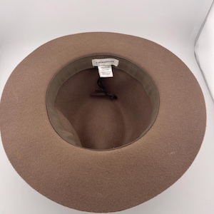 Puede incluir: Sombrero fedora marr&oacute;n con ala ancha. El interior presenta una banda verde oscuro y una etiqueta de marca. El sombrero est&aacute; hecho de un material suave similar al fieltro, ideal para a&ntilde;adir un toque de estilo a cualquier atuendo.