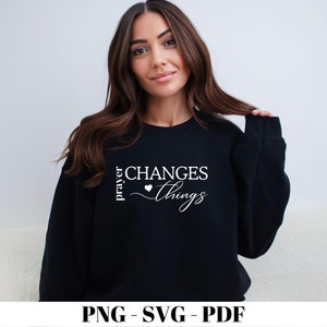 Peut inclure: Un sweat-shirt noir avec le texte "prayer changes things" en blanc avec un petit symbole de cœur.