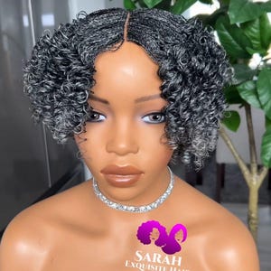 May include: A black and gray wig with a curly style. The wig is on a mannequin head. The wig is made of human hair and is labeled "Sarah Exquisite Hair".