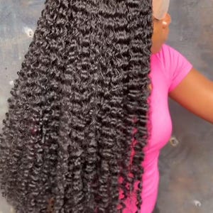 Può includere: Una lunga parrucca riccia scura con un frontale in pizzo. I capelli sono di un nero intenso e hanno una consistenza dall'aspetto naturale. La parrucca è acconciata con ricci voluminosi ed è probabilmente progettata per la moda o il cosplay.