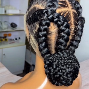 Peut inclure: Coiffure noire tressée avec des tresses épaisses et symétriques. Les tresses sont disposées en couronne autour de la tête, avec un chignon à la nuque. La coiffure est réalisée sur une tête de mannequin.