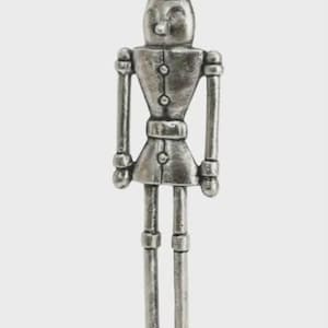 Puede incluir: Figura de cascanueces de metal plateado con cabeza cilíndrica y uniforme abotonado. La figura se apoya sobre una base rectangular de madera con un gancho. Un artículo decorativo para la temporada navideña.