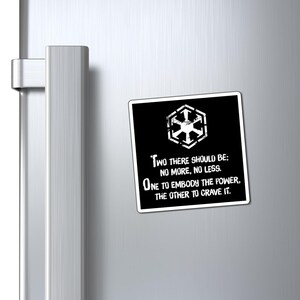 May include: A black and white magnet with the text "TWO THERE SHOULD BE; NO MORE, NO LESS. ONE TO EMBODY THE POWER, THE OTHER TO CRAVE IT." The magnet also features a white geometric symbol.