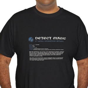 Puede incluir: Camiseta negra con el texto "DETECT MAGIC" y detalles de hechizos en blanco y azul. El diseño incluye un gráfico de un orbe azul. La camiseta tiene cuello redondo y es de tejido suave.