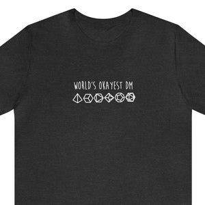 Puede incluir: Camiseta gris oscuro jaspeada con el texto "World's Okayest DM" y una fila de iconos de dados blancos.