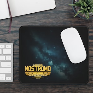 以下が含まれることがあります： 暗い青色の星雲の背景と「USCSS NOSTROMO 180286 Weyland-Yutani Corporation」と書かれた金色のロゴが付いた黒いマウスパッド