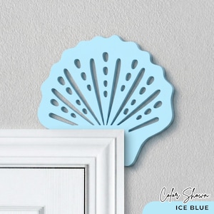 May include: A light blue, fan-shaped wall decor piece with a scalloped edge and a series of cut-out designs. The decor is mounted on a light gray wall, and the color is labeled as "Ice Blue".