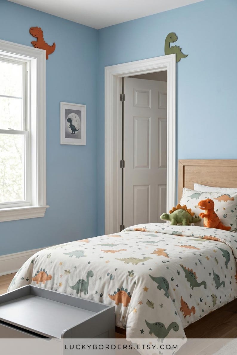 Puede incluir: Un dormitorio infantil con una pared azul claro, una cama con una funda n&oacute;rdica con tem&aacute;tica de dinosaurios y una cabecera de madera. Recortes de dinosaurios decoran la pared. Una imagen enmarcada de un dinosaurio est&aacute; en la pared. El texto "LUCKYBORDERS.ETSY.COM" est&aacute; en la parte inferior.