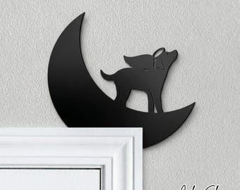 May include: Black metal wall art featuring a dog with angel wings standing on a crescent moon. The dog is looking up. The text "Color Shown: BLACK" is at the bottom right.