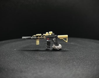May include: A black and gold toy replica of an assault rifle with a red and white sticker on the side. The toy is on a black surface.
