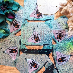 May include: A set of eight iridescent holographic stickers featuring a whimsical illustration of a sailboat with three eyes. The stickers are square shaped and have a glittery background.