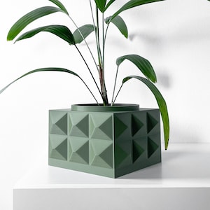 Peut inclure: Un pot de fleurs géométrique vert avec une plante d'intérieur aux longues feuilles vertes.