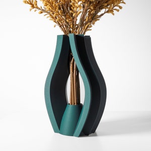 May include: A teal blue ceramic vase with a unique, abstract design. The vase is made of multiple curved panels that create a modern and stylish look. The vase is empty, but it would be perfect for displaying flowers or other decorative items.
