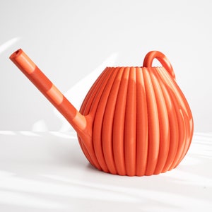 Może przedstawiać: Pomarańczowa plastikowa konewka z żebrowanym wzorem i długim wylewką.