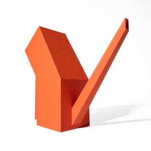 Könnte beinhalten: Eine leuchtend orangefarbene geometrische Skulptur mit rechteckiger Basis und langem, abgewinkeltem Ausguss. Die Skulptur besteht aus massivem Material und wirft einen Schatten auf den weißen Hintergrund. Das Design ist modern und abstrakt.