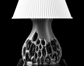 May include: A white lampshade with a pleated design sits atop a silver base with a unique, organic, honeycomb-like pattern.