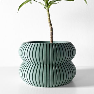 May include: A light green ceramic planter with a ribbed design. The planter has two tiers and is ideal for displaying a houseplant.