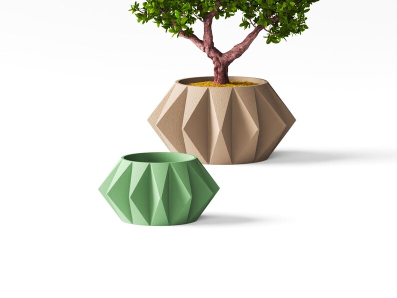 May include: Two geometric planters with a faceted, diamond-like surface texture. One planter is a muted sage green, while the larger, beige planter contains a small tree with a textured reddish-brown trunk and vibrant green leaves.