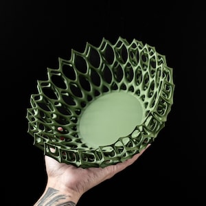May include: A green, 3D printed bowl with a geometric, lattice design. The bowl is made of a lightweight, durable material and has a smooth, matte finish.
