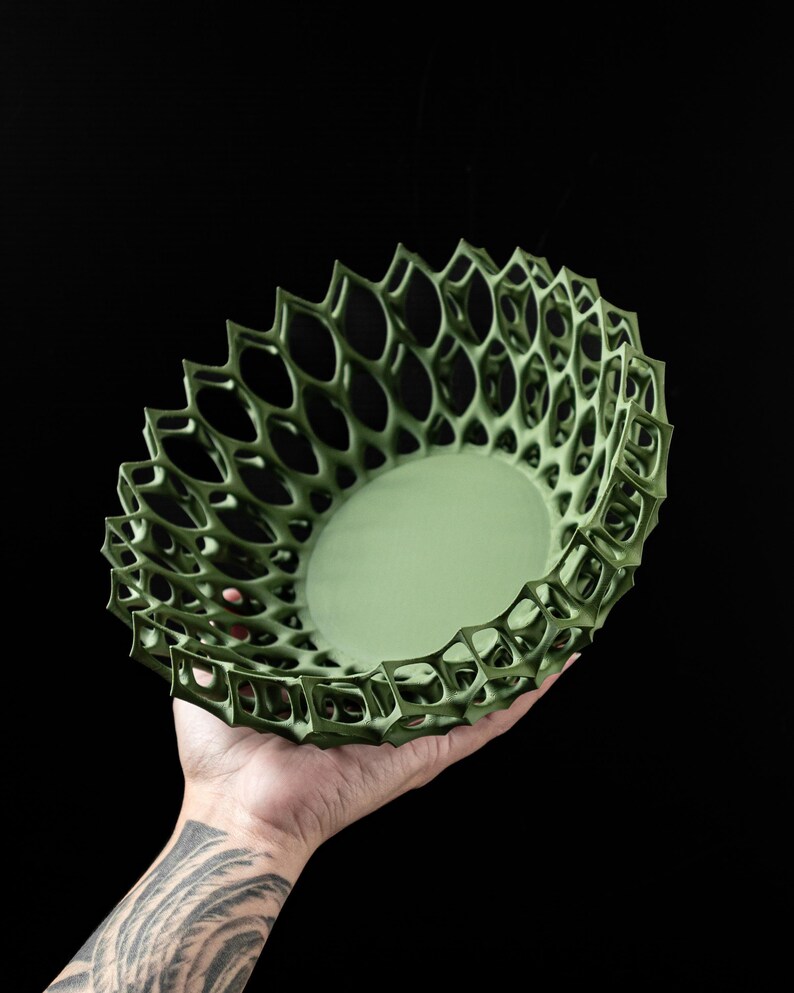 May include: A green, 3D printed bowl with a geometric, lattice design. The bowl is made of a lightweight, durable material and has a smooth, matte finish.