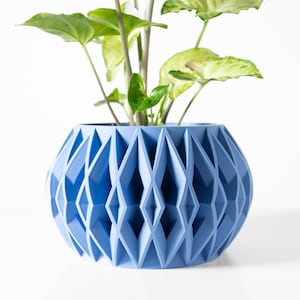 May include: A light blue geometric planter with a plant inside. The planter has a diamond pattern and is made of ceramic.