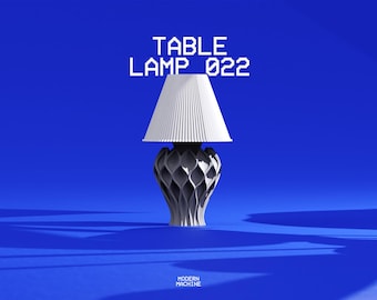 Op de afbeelding: Een tafellamp met een witte geplooide conische kap en een donkergrijze, complexe, rastervormige voet. De tekst "TABLE LAMP 022" staat boven de lamp en "MODERN MACHINE" staat in kleine witte letters onderaan in het midden.