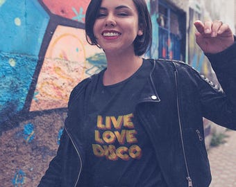 May include: A woman wearing a black leather jacket over a black t-shirt with the text "LIVE LOVE DISCO" in yellow and orange letters. The text is in a retro font style.