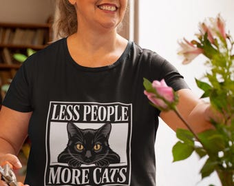 May include: Black t-shirt with the text "LESS PEOPLE MORE CATS" in a white box, featuring a black cat with yellow eyes. The shirt is a crew neck style.