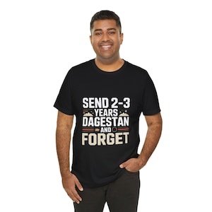 Puede incluir: Camiseta negra con el texto "SEND 2-3 YEARS DAGESTAN AND FORGET" en blanco y rojo. La camiseta tiene cuello redondo y mangas cortas. El texto está centrado en la parte delantera de la camiseta.