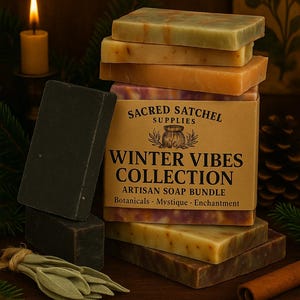 Könnte beinhalten: Eine Auswahl handgemachter Seifen aus der Winter Vibes Kollektion in verschiedenen Farben, darunter Grün, Braun und Lila. Die Seifen sind auf einer Schachtel mit der Aufschrift "Sacred Satchel Supplies" und "Winter Vibes Collection" gestapelt.