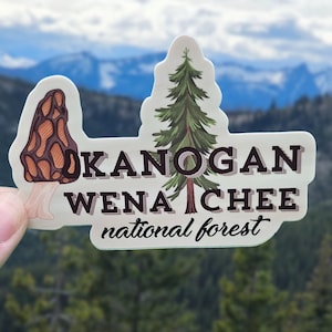 May include: A sticker with a brown and orange mushroom, a green pine tree, and the text "OKANOGAN WENATCHEE national forest".