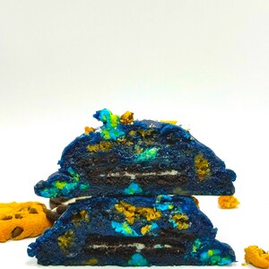 Könnte beinhalten: Zwei blaue Kekse mit einer Schicht Schokolade und weißer Zuckerglasur dazwischen. Die Kekse sind mit gelben und blauen Streuseln verziert.