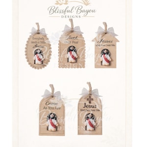 May include: A collection of five wooden tags with religious themes. Each tag features a small Jesus figurine and a white ribbon. The tags have different shapes and include phrases like "Everybody needs a little Jesus" and "Faith Over Fear."